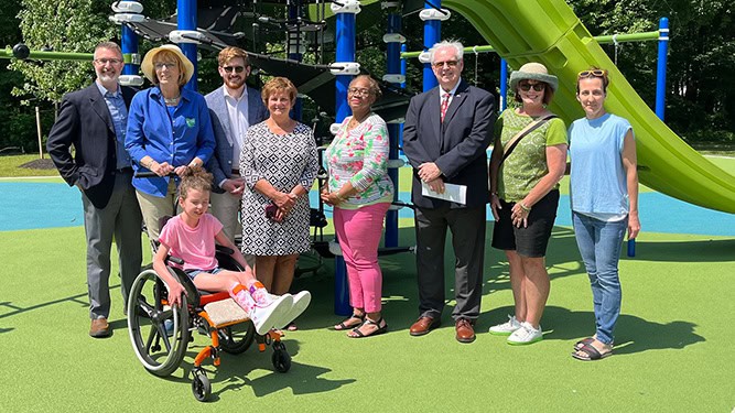 Secretary Cindy Adams Dunn stands in group photo with Lower Paxton Township Officials, child in wheelchair at Brightbill Park