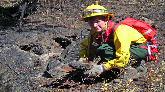 A firefighter poses for a photo while holiding a rock.