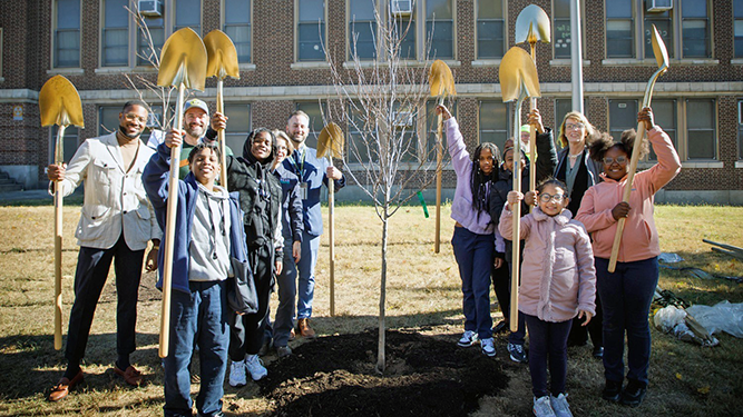 Department of Conservation and Natural Resources staff and local students pose in front of a newly-planted tree.