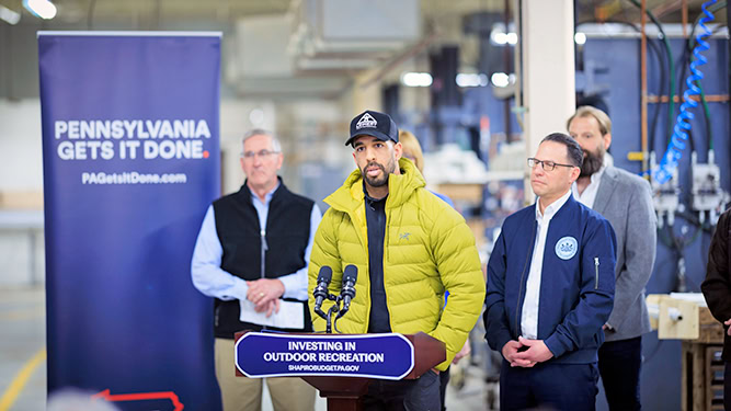 Outdoor Inclusion Coalition member Marcus Shoffner speaks at a podium that reads 